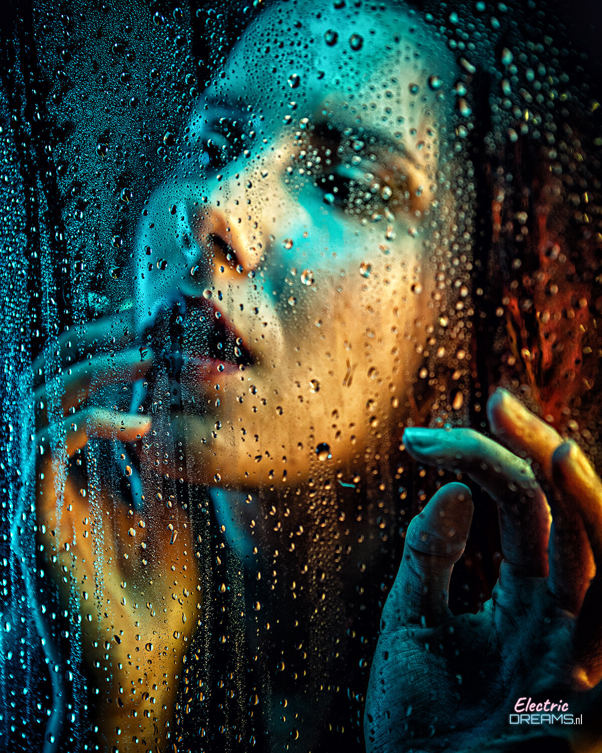 The image shows a woman looking out of a window with water droplets on it, her face illuminated by the light coming through the glass.