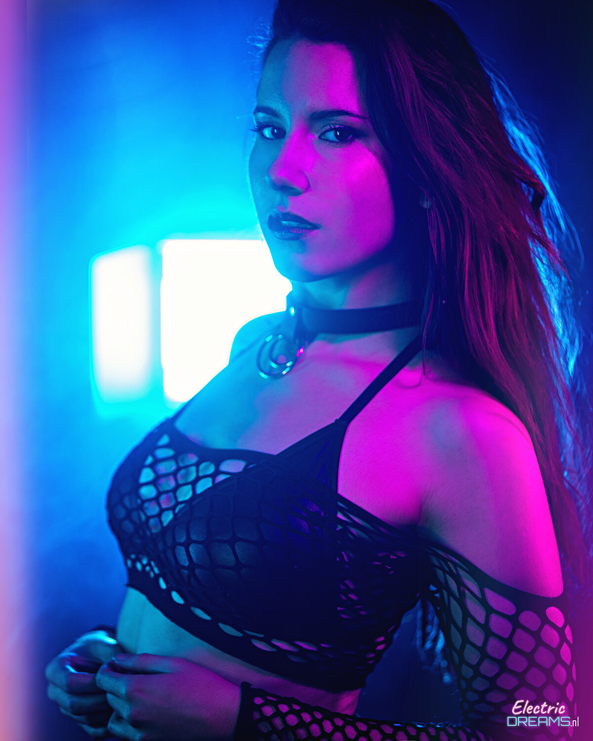 The image shows a woman in a black dress standing in front of a neon light, with a watermark in the bottom right corner.