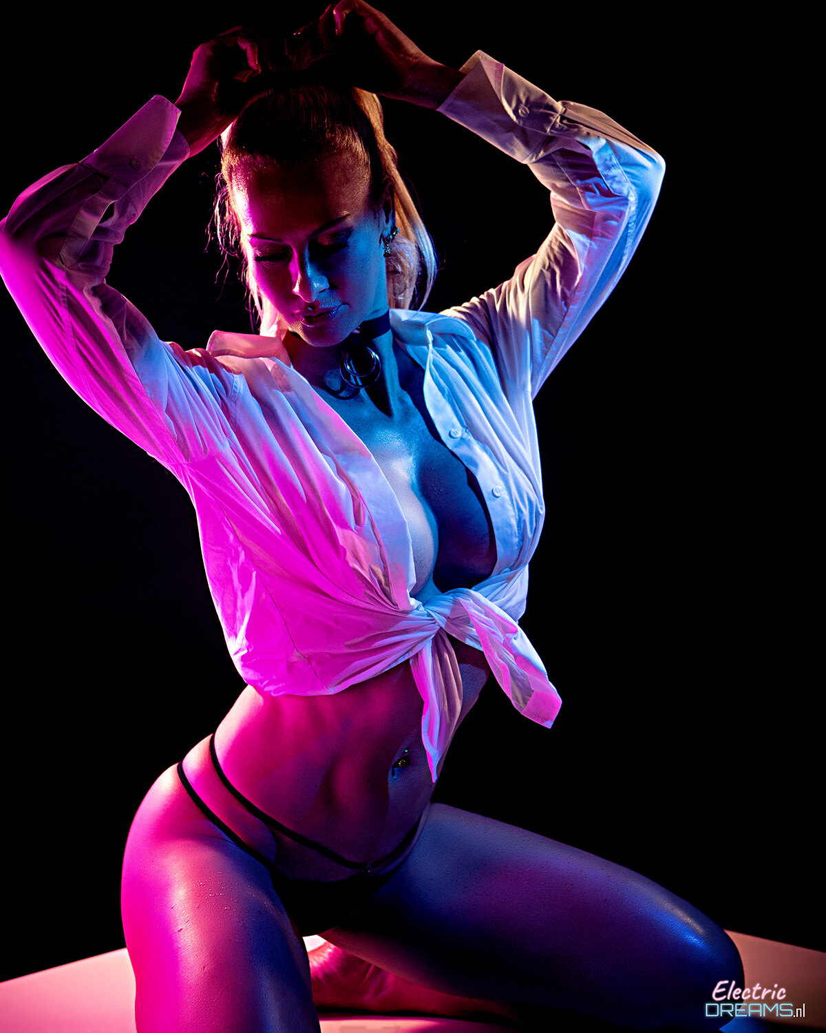 The image shows a woman in a white shirt and black pantyhose posing for a picture against a dark background with a watermark.